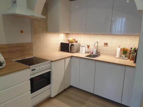 a kitchen with white cabinets and a sink and a microwave at Sopot City Apartment in Sopot