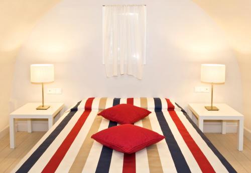 a bedroom with a striped bed with two lamps at Meltemi Village Hotel in Perissa
