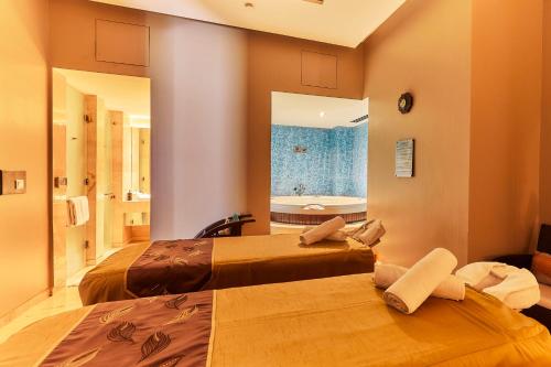 two beds in a room with a bathroom with a tub at Crowne Plaza New Delhi Rohini by IHG in New Delhi