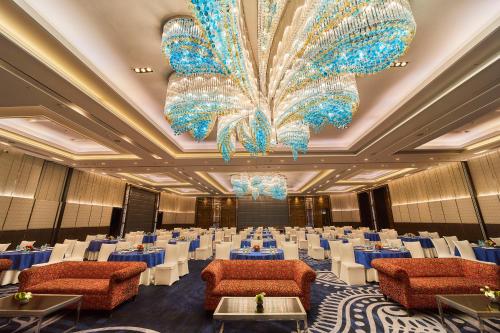 a banquet hall with blue tables and chairs and a chandelier at Crowne Plaza New Delhi Rohini by IHG in New Delhi