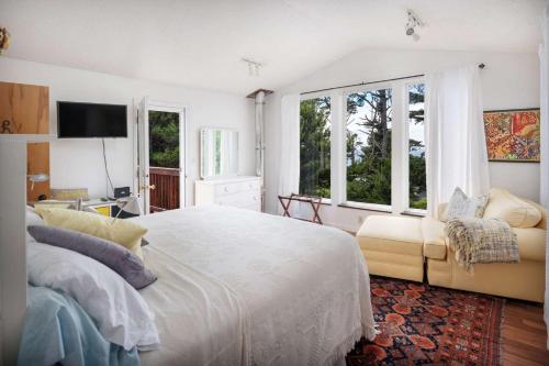 a bedroom with a bed and a couch and windows at Fernglen Forested Beach Retreat in Lincoln Beach