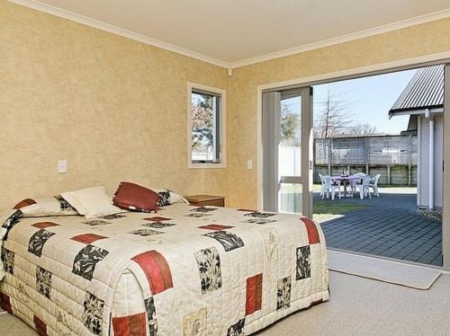 Schlafzimmer mit einem Bett und einer Glasschiebetür in der Unterkunft Lochaber Lodge - Acacia Bay Holiday Home in Taupo