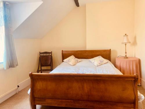 a bedroom with a wooden bed and a chair at Lavender Cottage in Hereford