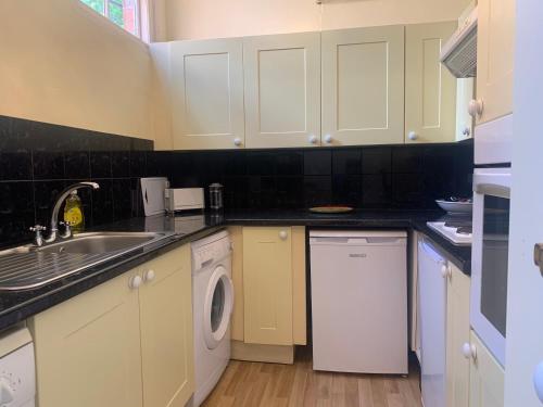 a kitchen with white cabinets and a washer and dryer at Lavender Cottage in Hereford