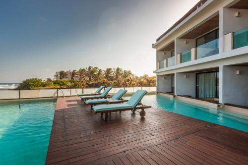 una fila de tumbonas sentadas en una terraza junto a una piscina en O' Tulum Boutique Hotel - Adults Only, en Tulum
