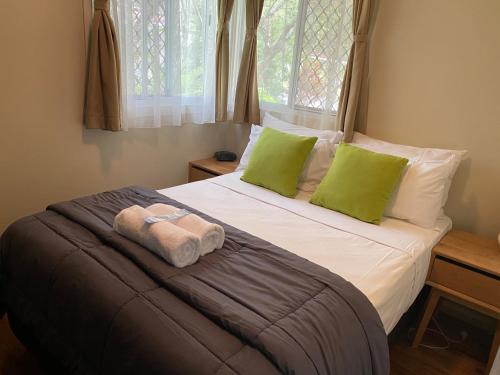 Una cama con almohadas verdes y una toalla. en NRMA Atherton Tablelands Holiday Park, en Atherton