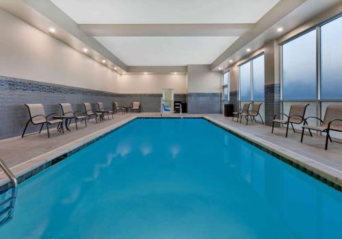 ein großer Pool mit Stühlen und Tischen in einem Gebäude in der Unterkunft La Quinta Inn & Suites by Wyndham Lewisville in Lewisville