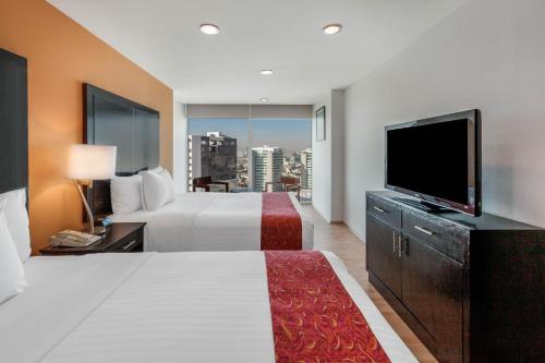 a hotel room with a bed and a flat screen tv at La Quinta by Wyndham Puebla Palmas Angelopolis in Puebla