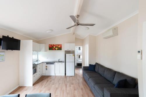 a living room with a couch and a kitchen at Crestview Tourist Park in Queanbeyan