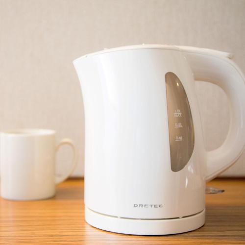 a white toaster sitting on a table next to a cup at Super Hotel Kadoma in Kadoma
