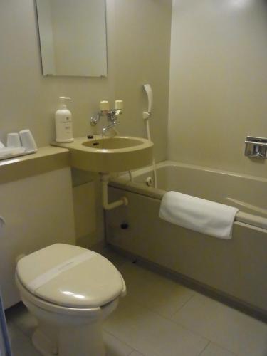 a bathroom with a toilet and a sink and a tub at Hotel New Mogamiya in Yamagata