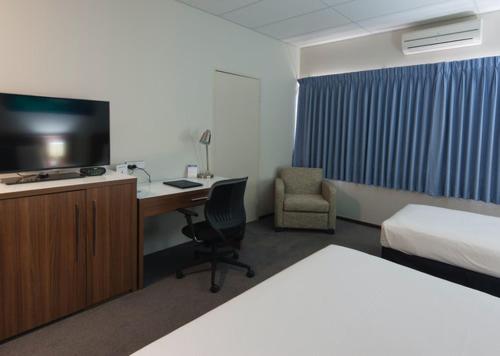 Habitación de hotel con cama y escritorio con TV. en Ocean Centre Hotel, en Geraldton