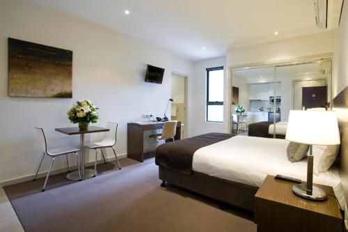 Habitación de hotel con cama, mesa y escritorio. en Quest Glen Waverley, en Glen Waverley