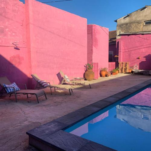 a swimming pool with two chairs and a pink wall at São Miguel House , Casa do Carvalhal in Santarém