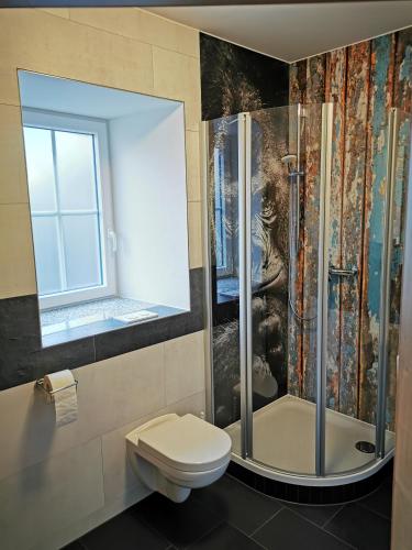 a bathroom with a shower and a toilet and a window at Pension unterm Schlossturm in Haag in Oberbayern