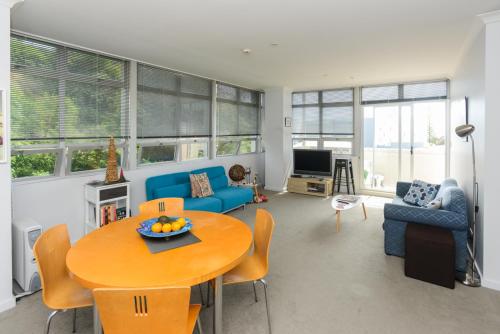 a living room with a table and a blue couch at Napier Inner City Apartment - Napier Apartment in Napier
