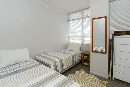 a small bedroom with two beds and a mirror at Napier Inner City Apartment - Napier Apartment in Napier