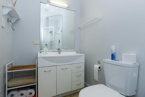 y baño con aseo, lavabo y espejo. en Napier Inner City Apartment - Napier Apartment en Napier