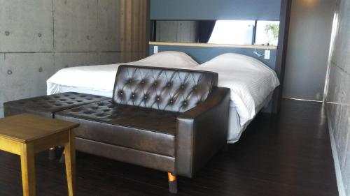 a bedroom with a bed and a leather chair at Blue Suites Hanamuro in Zamami