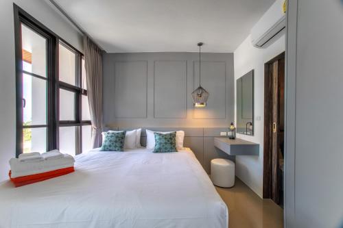 a bedroom with a large white bed and windows at 2BDR Apartment near Surin beach #703 in Surin Beach