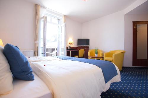 a hotel room with a large bed and yellow chairs at Hotel Meeresruh Garni in Cuxhaven