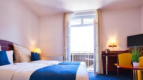 a hotel room with a bed and a desk and a window at Hotel Meeresruh Garni in Cuxhaven