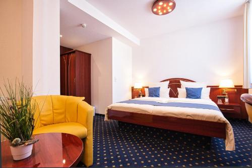 a hotel room with a bed and a yellow chair at Hotel Meeresruh Garni in Cuxhaven