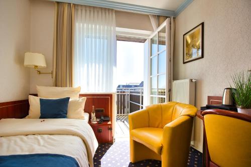 a hotel room with a bed and a yellow chair at Hotel Meeresruh Garni in Cuxhaven