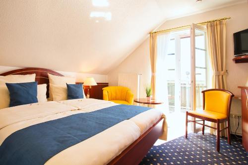 a bedroom with a large bed and yellow chairs at Hotel Meeresruh Garni in Cuxhaven