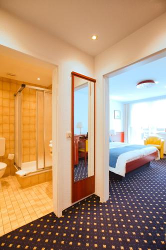 a hotel room with a bed and a bathroom at Hotel Meeresruh Garni in Cuxhaven