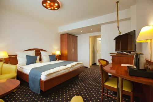 a hotel room with a bed and a desk and a television at Hotel Meeresruh Garni in Cuxhaven