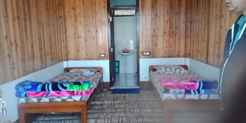 two beds in a room with wooden walls at Vamoose Shri Ganesh Homestay in Māngwa