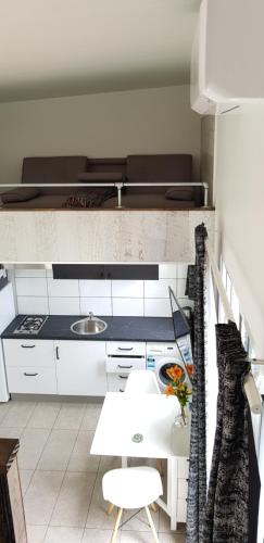 a kitchen with white cabinets and a white table at Alexandra Headland in Alexandra Headland