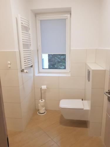 uma casa de banho branca com um WC e uma janela em Apartamenty KADO em Karpacz