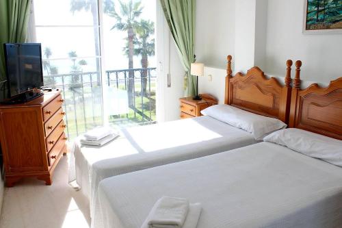 1 Schlafzimmer mit 2 Betten, einem TV und einem Balkon in der Unterkunft Hacienda Beach in Estepona