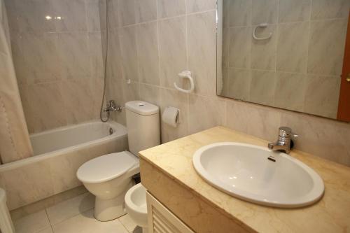 a bathroom with a sink and a toilet and a mirror at AT031 Comunidad con 2 piscinas, a 5 min a pie de la playa in Torredembarra