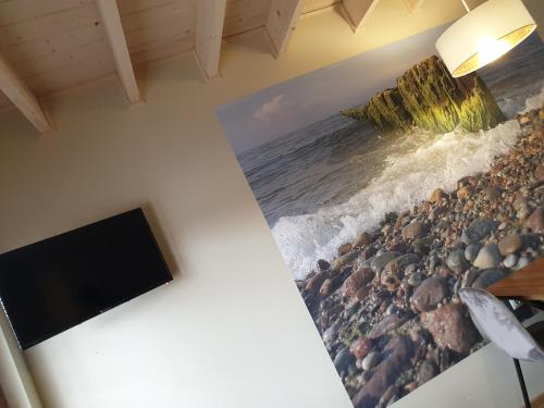 a room with a tv and a painting of the ocean at OSADA CZTERY PORY ROKU - DOM WIOSNA in Kopalino