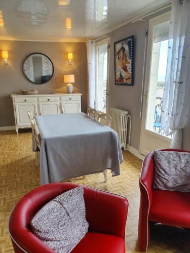 un salon avec une table et une chaise rouge dans l'établissement 180° VUE MER, au Tréport