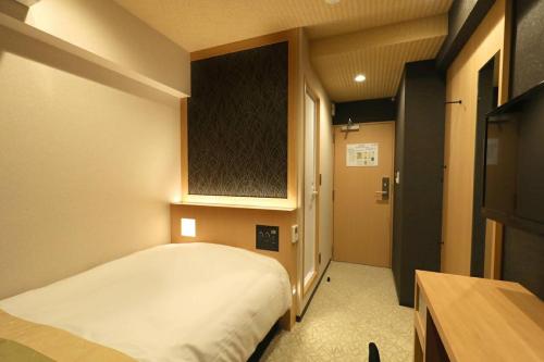 a small bedroom with a bed and a television at Hotel Matsunoi in Tokyo