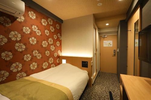 a bedroom with a bed and a wall with flowers at Hotel Matsunoi in Tokyo