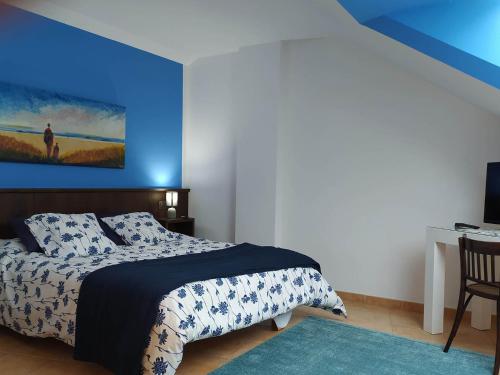 1 dormitorio con cama y pared azul en Hotel Entreviñes en Colunga