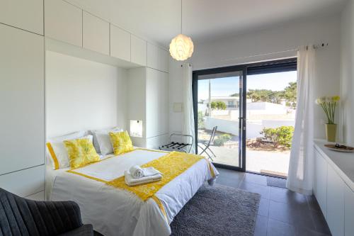 una camera da letto con un letto grande con cuscini gialli di Biscuttela Vicentina a Praia da Arrifana