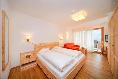 a bedroom with a large white bed and a chair at Hotel Niedermair in Parcines