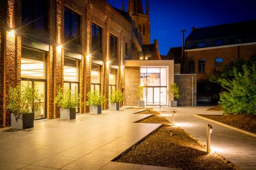 a building with potted plants in a courtyard at night at Albion Hotel in Ieper