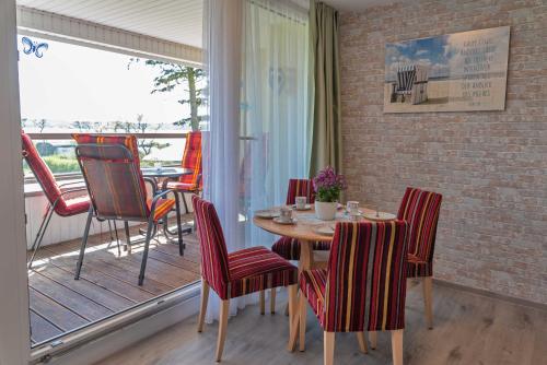 een eetkamer met een tafel en stoelen en een balkon bij Haus Inselperle mit Blick auf den Bodden in Alt Reddevitz