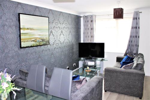 a living room with two chairs and a television at Homely and Budget Friendly 3 bed house Sleeps 6 Free Parking! in Milton Keynes