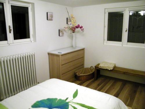 ein Schlafzimmer mit einem Bett und einer Blumenvase auf einer Kommode in der Unterkunft Grand appartement dans villa avec parking quartier résidentiel in Joigny
