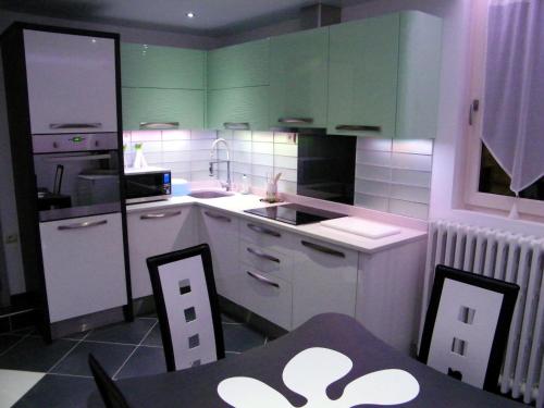 una cucina con armadi verdi, tavolo e sedie di Grand appartement dans villa avec parking quartier résidentiel a Joigny