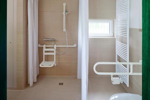 a bathroom with a shower and a toilet and a window at AS Feriendorf in Wangerland