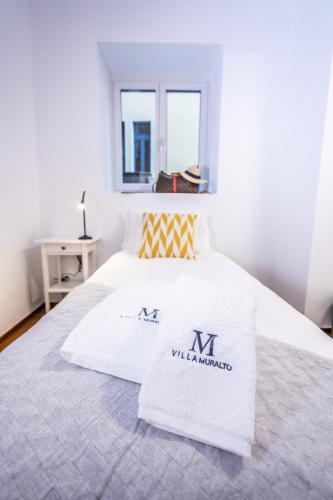 a white bed with two white towels on it at VILLA MURALTO Boutique Hotel Rooms and Garden in Locarno